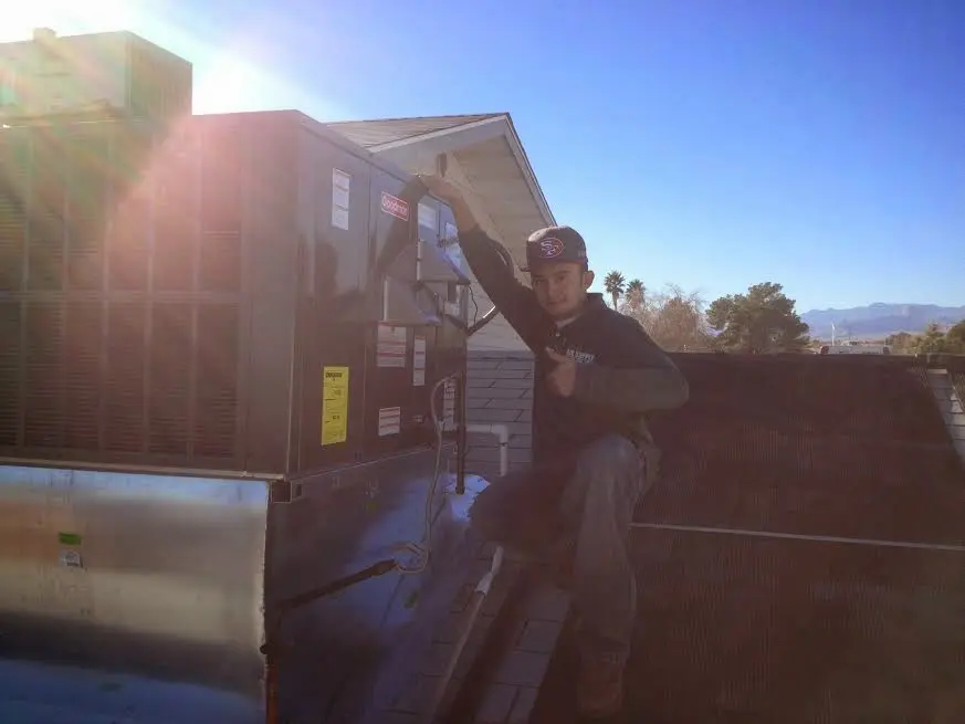 HVAC technician performing AC Tune-Up on a rooftop unit in Troy